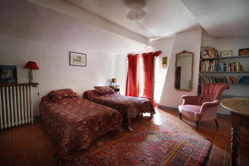 - une chambre avec deux lits, une chaise et un miroir dans l'établissement Maison du Loup, à Ganges