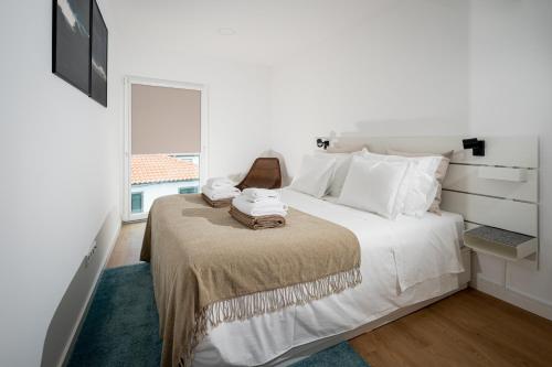 Un dormitorio blanco con una cama con toallas. en The Wish São Roque, en Ponta Delgada