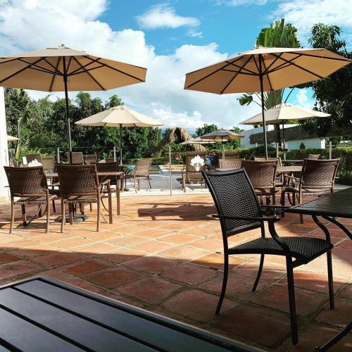 an outdoor patio with tables and chairs with umbrellas at La Masia Hotel Boutique in Anapoima