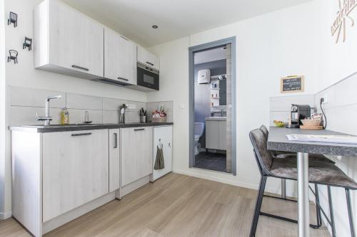 une cuisine avec des placards blancs, un comptoir et une table dans l'établissement LB Vacation Rentals I Cute Affordable 1-Br Minutes From Cannes Center, à Cannes