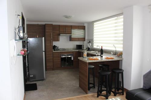 a kitchen with a refrigerator and some bar stools at Suit Torre Sofia in Quito