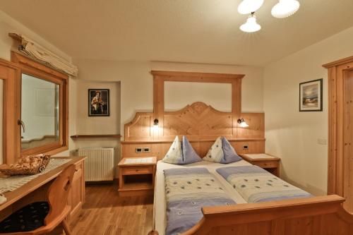 a bedroom with a large bed with a wooden headboard at Ciasa Mirio' in La Valle
