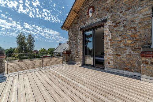 una gran terraza de madera junto a un edificio de piedra en Les Villas de Locmiquel BORD DE MER, en Baden