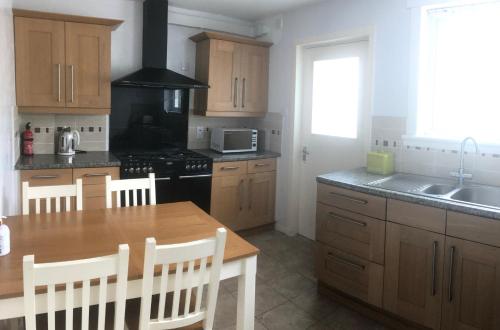 a kitchen with a wooden table and a stove top oven at Tigh Na Mara Holiday Home in Aultbea
