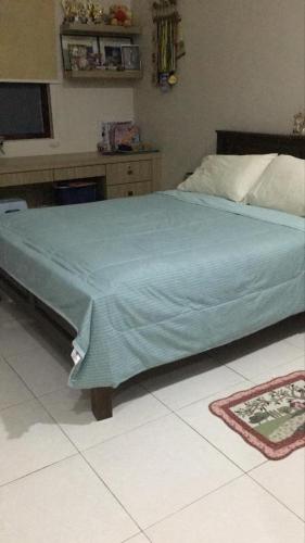 a bedroom with a bed with a blue blanket on it at BM Rooms in Bukit Mertajam