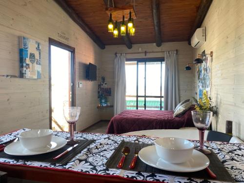 Cette chambre comprend une table avec deux assiettes et des verres à vin. dans l'établissement Piedra y Cielo, à Punta del Diablo