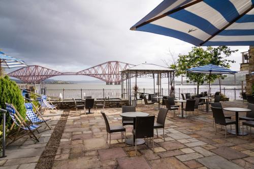 a patio with tables and chairs and a bridge at Orocco Pier in Queensferry