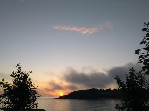 a sunset over a body of water with trees at Camping Paxariñas in Portonovo