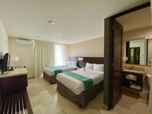 a hotel room with two beds and a mirror at Seven Crown La Paz Malecon in La Paz