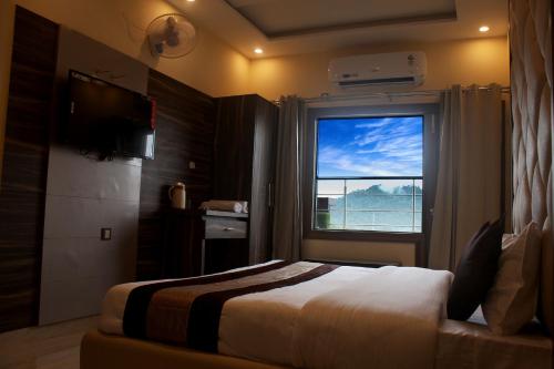 um quarto de hotel com uma cama e uma janela em Hotel Ganga Heights em Haridwar
