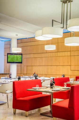 a restaurant with tables and red chairs and a tv at Fiesta Inn Insurgentes Viaducto in Mexico City
