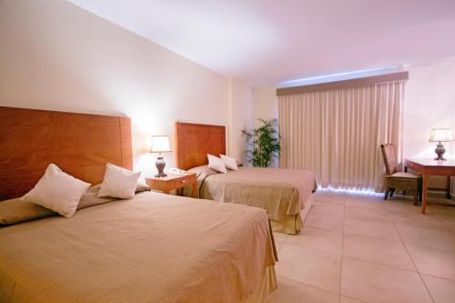 a hotel room with two beds and a desk at Hotel Arenas del Mar Resort in Tampico