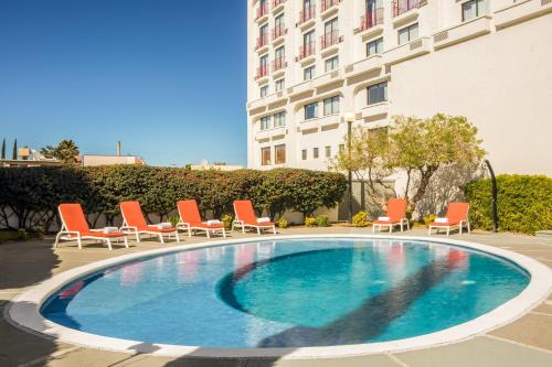 a swimming pool with lounge chairs and a building at Fiesta Inn Chihuahua in Chihuahua