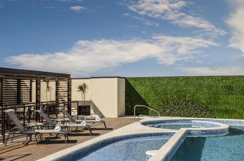 a patio with a swimming pool and chairs and a patio with a fence at Fiesta Inn Express Queretaro Constituyentes in Querétaro