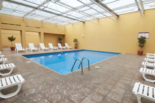 a large pool with white chairs and a swimming pool at Fiesta Inn Toluca Tollocan in Toluca