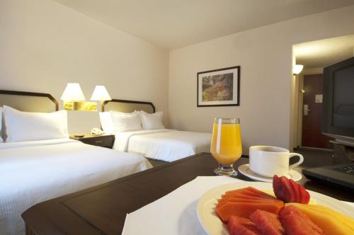a hotel room with a plate of fruit and a glass of orange juice at Fiesta Inn Toluca Tollocan in Toluca