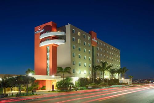 a hotel with a red and white building at night at Fiesta Inn Tijuana Otay Aeropuerto in Tijuana