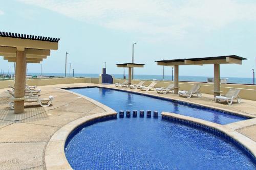 a swimming pool with chairs and the ocean in the background at Fiesta Inn Coatzacoalcos in Coatzacoalcos