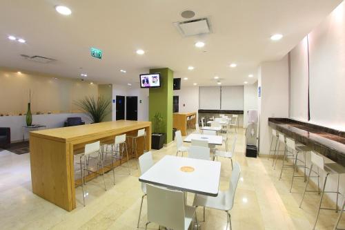 un restaurante con mesas y sillas blancas y TV en One Culiacan Forum en Culiacán