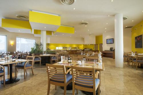 un restaurant avec des tables et des chaises en bois et des murs jaunes dans l'établissement Fiesta Inn Mexicali, à Mexicali