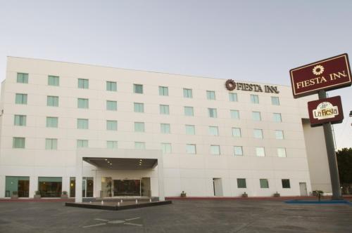 a white building with a sign in front of it at Fiesta Inn Mexicali in Mexicali