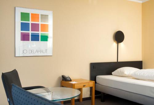a hotel room with a bed and a table and a phone at Hotel Excelsior Ludwigshafen in Ludwigshafen am Rhein