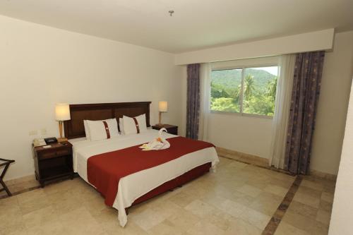 a bedroom with a large bed with a large window at Gamma Plaza Ixtapa in Ixtapa