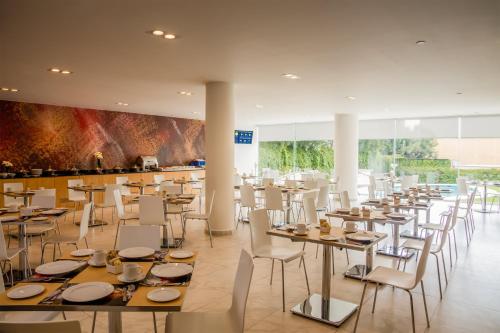 a dining room with tables and white chairs at Fiesta Inn Express Perinorte in Mexico City
