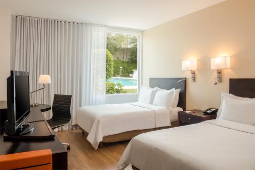 a hotel room with two beds and a television at Fiesta Inn Perinorte in Mexico City