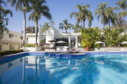 a swimming pool in front of a house with palm trees at Gamma Cuernavaca Puerta Paraiso in Cuernavaca