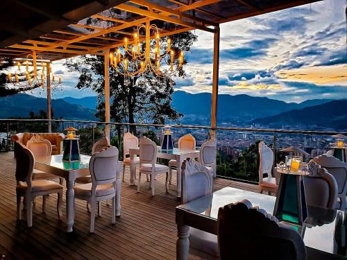 a restaurant with tables and chairs on a deck with a view at HOTEL BOUTIQUE EL FARO BY AROMAX in Medellín