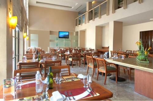 une salle à manger avec des tables et des chaises en bois dans l'établissement Fiesta Inn Poza Rica, à Poza Rica de Hidalgo