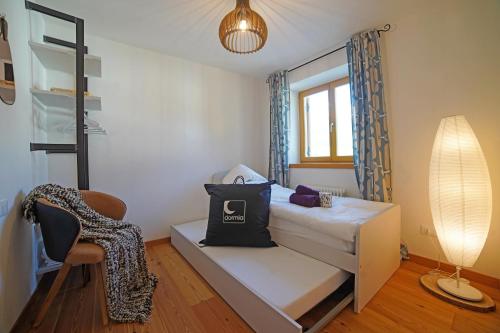 a small bedroom with a bed and a chair at Design Residence Del Passo in Padola