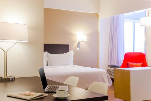 a hotel room with a bed and a desk with a laptop at Fiesta Inn Tlalnepantla in Mexico City