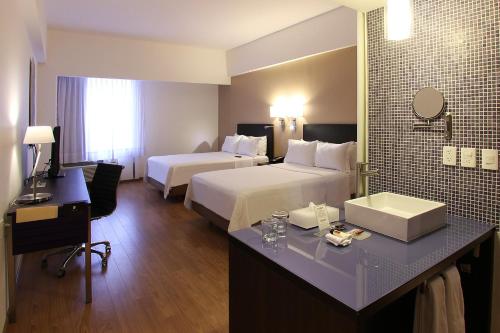 a hotel room with two beds and a desk at Fiesta Inn Tlalnepantla in Mexico City