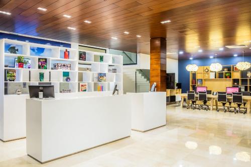 an office lobby with a white counter and chairs at Fiesta Inn Playa del Carmen in Playa del Carmen