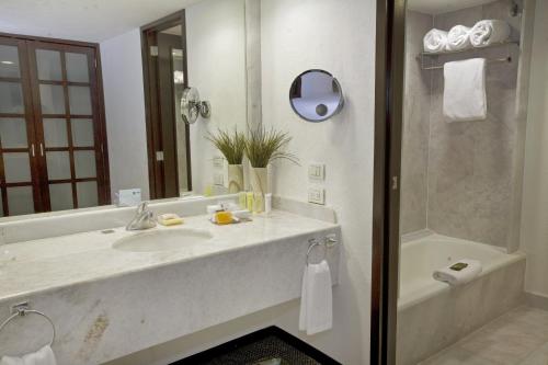 a bathroom with a sink and a mirror and a tub at Fiesta Americana Guadalajara in Guadalajara