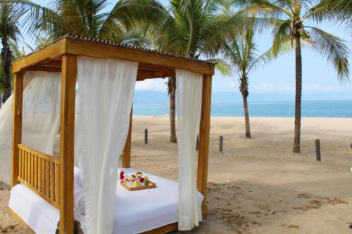 a canopy bed on the beach with palm trees at Fiesta Americana Puerto Vallarta All Inclusive & Spa in Puerto Vallarta