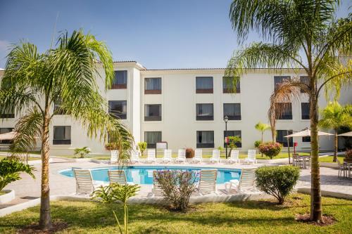 um hotel com piscina e palmeiras em Fiesta Inn Monterrey la Fe em Monterrey
