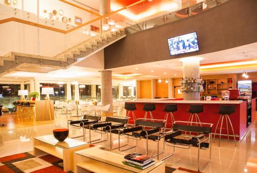 a lobby with chairs and a bar with a tv at Fiesta Inn Queretaro Centro Sur in Querétaro
