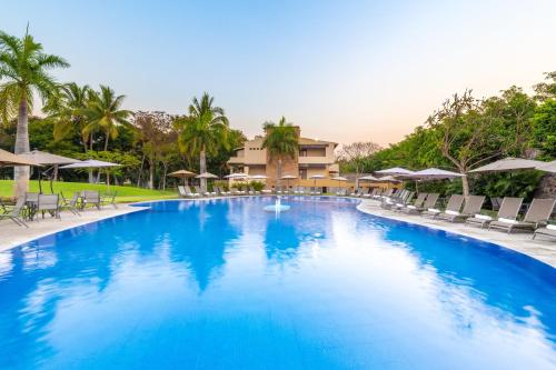 uma grande piscina com cadeiras e guarda-sóis num resort em Fiesta Americana Hacienda San Antonio El Puente Cuernavaca em Cuernavaca