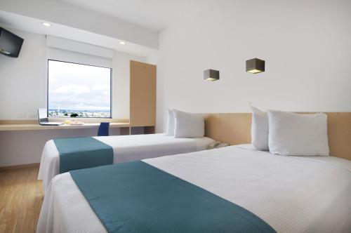 Habitación de hotel con 2 camas y ventana en One Toluca Aeropuerto en Toluca