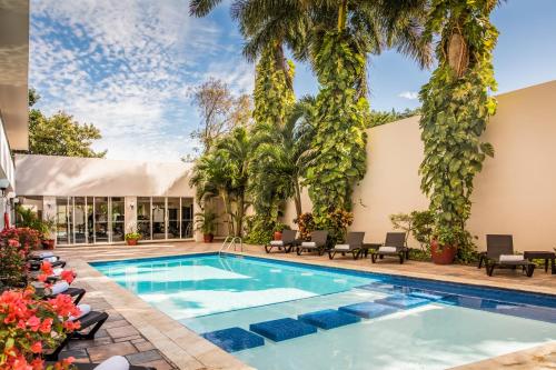 une piscine bordée de palmiers et un bâtiment dans l'établissement Gamma Merida El Castellano, à Mérida