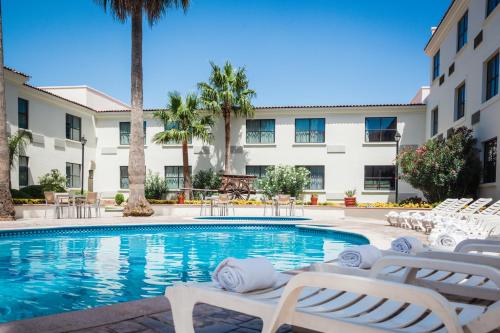 a swimming pool with chairs and a building at Fiesta Inn Saltillo in Saltillo