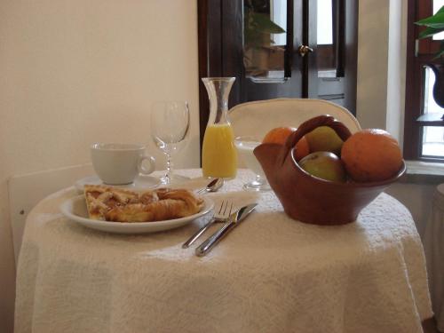 un tavolo con un piatto di cibo e un cesto di frutta di Guest House Il Giardino Segreto a Cagliari