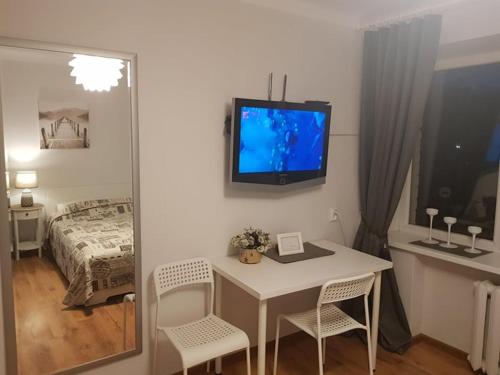 Zimmer mit einem Tisch und einem TV an der Wand in der Unterkunft Karoso Apartment in Klaipėda