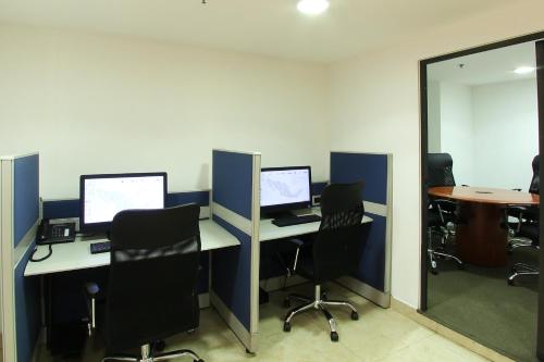 an office with three computer desks with chairs and a mirror at One Guadalajara Centro Historico in Guadalajara