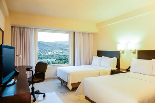 a hotel room with two beds and a window at Fiesta Inn Tuxtla Gutierrez in Tuxtla Gutiérrez