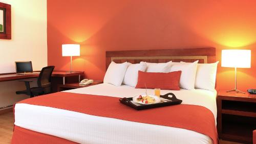 a hotel room with a bed with a tray of food on it at Fiesta Inn Villahermosa Cencali in Villahermosa