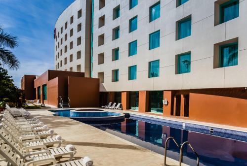 uma piscina do hotel com espreguiçadeiras ao lado de um edifício em Fiesta Inn Culiacan em Culiacán